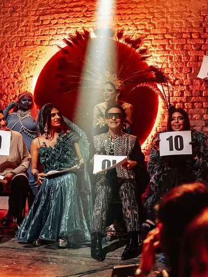 A fun moment on set with Sushant Divgikr judging a ball. The makeup here is theatrical and expressive, perfect for the vibrant and celebratory atmosphere of the event.