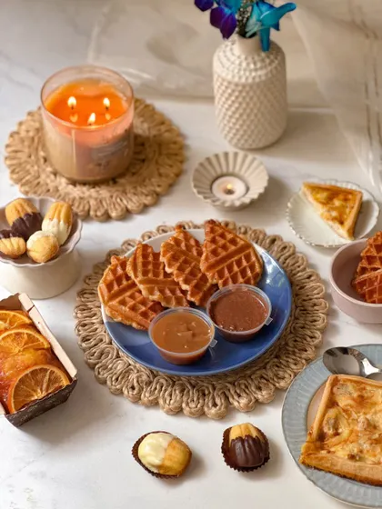 A beautiful flat-lay of the Father's Day brunch spread, including waffles with dips, a slice of quiche, and candied orange tea cake.