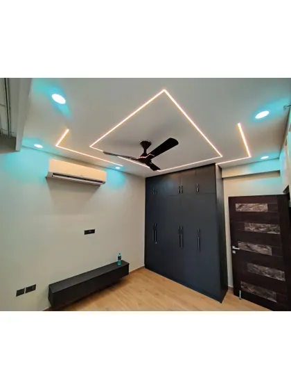 A bedroom that combines modern design with practical storage solutions. The floating TV unit and floor-to-ceiling wardrobe in a dark finish provide a sleek and functional space.