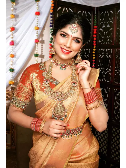 This bride is glowing in a gold saree and a beautiful kemp jewellery set. The combination of the choker, haram, and waist belt is perfect for a traditional Muhurtham.
