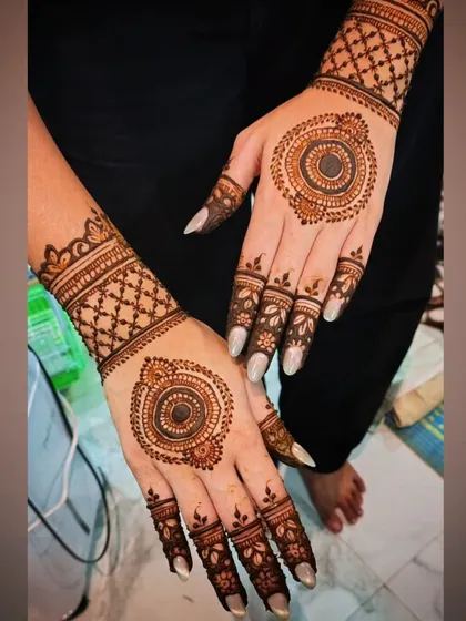 A chic and modern mehendi design featuring bold circular mandalas on the back of the hands, paired with geometric wrist cuffs and detailed finger patterns.