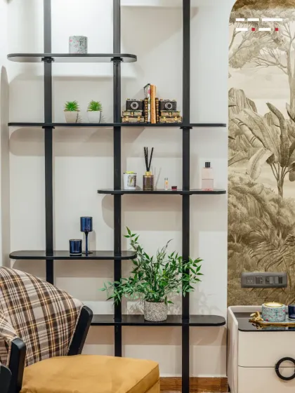 This minimalist black shelving unit provides stylish, open storage for books and decor, complementing the botanical theme of the bedroom without taking up floor space.
