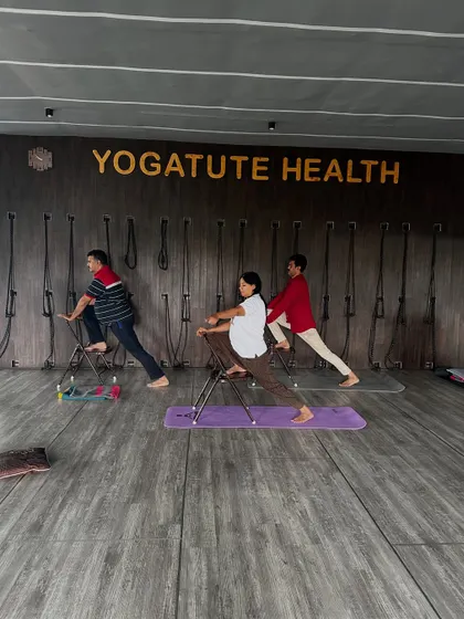A supported lunge using a chair. This modification allows students to work on hip flexibility and leg strength without putting excessive pressure on the joints.