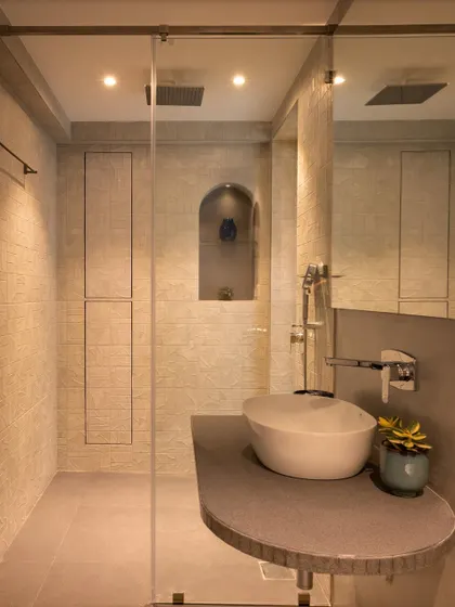 This angle of the master bathroom highlights the curved vanity counter and vessel sink. The warm, ambient lighting and seamless storage panels contribute to a serene and spa-like atmosphere.