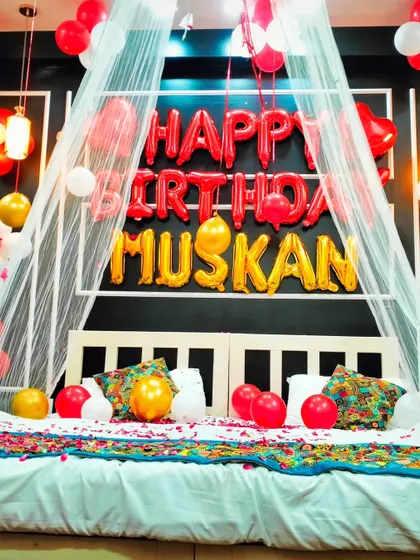 A close-up of the romantic bedroom setup for "Muskan", focusing on the "Happy Birthday" foil balloons and the canopy over the bed.
