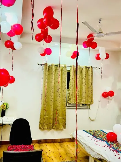 A wider view of the romantic room decoration, showing balloons floating on the ceiling with ribbons, adding to the celebratory atmosphere.