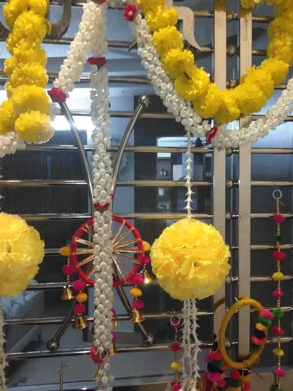 Detailed decoration on a window grill using marigold garlands and other colorful hangings.