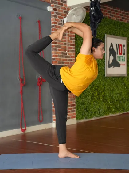 A standing backbend, grabbing the ankle in a variation of Natarajasana (Dancer's Pose). This requires balance and a deep opening in the quadriceps and psoas muscles.