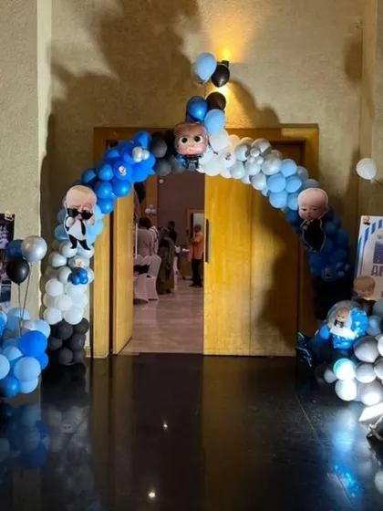 A Boss Baby themed balloon arch at the entrance of a party. The blue, white, and black balloons with character toppers give guests a fun welcome.