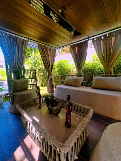 Sunlight streams into the pergola, creating a bright and airy daytime lounge. The curtains can be drawn for more shade or privacy.