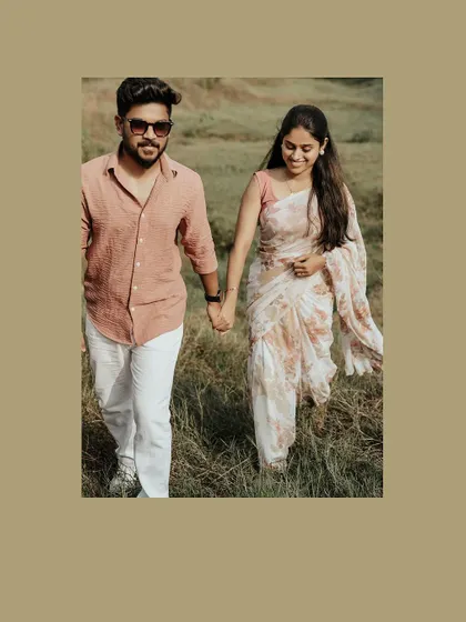 A happy couple walks hand-in-hand through a field, a perfect candid moment.