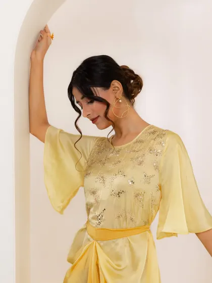Another look from the A.Projekt campaign, this time a draped yellow midi dress. The styling against the arched, minimalist set was designed to highlight the garment's modern silhouette and delicate embroidery.