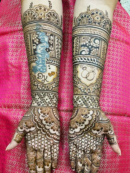 An engagement mehendi with a special touch. The bride's name, 'Divya', is written in a beautiful script on one arm, with the couple's initials 'DK' below it.