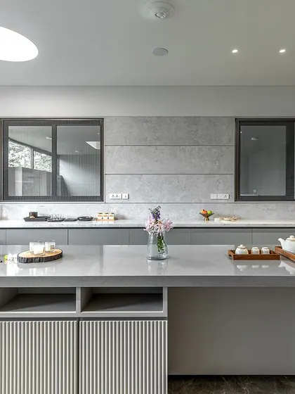 The island in Niketa Lalit Patel's kitchen features open shelving and a unique ribbed texture on the drawer fronts, adding a subtle decorative detail to the minimalist design.