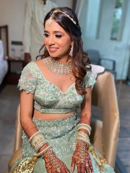A candid moment of Aashna seated, looking radiant and ready for her big day. The makeup looks flawless from every angle, ensuring she is picture-perfect.