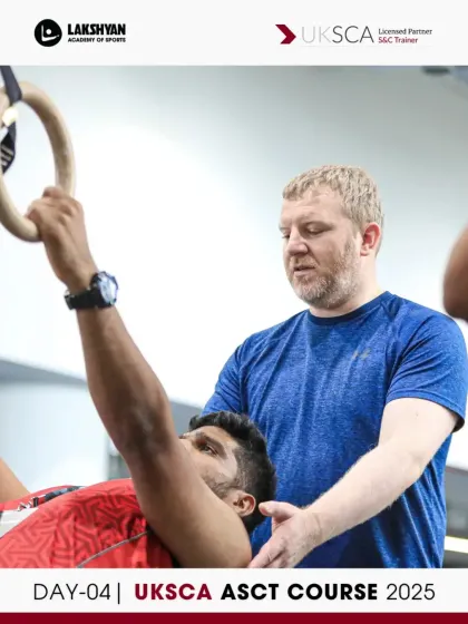 A UKSCA trainer provides hands-on guidance for an inverted row using gymnastic rings, a key upper body strength exercise covered on Day 4.