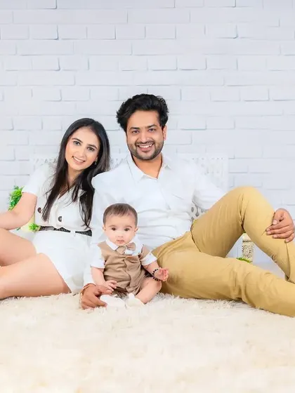 A bright and airy family portrait. The family is dressed in light, neutral colors, creating a fresh and modern feel on a white brick background.