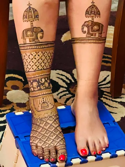 A unique design with a single leg adorned with full-coverage mehendi, featuring an elephant with an umbrella.