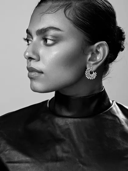 A close-up beauty shot for a fine diamond jewelry brand. The clean lighting and sharp focus highlight the intricate design of the earrings and the model's flawless skin.