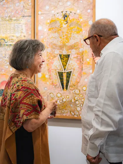 Artist Eva Malhotra in conversation with a guest at the 'Call to the Mystic' exhibition, sharing the stories behind her work.