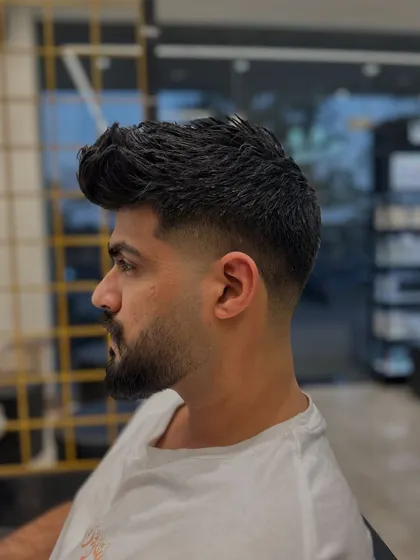This is a great example of how a fade and beard can work together. The hair fades down to the skin and then blends back into the full, well-defined beard for a strong, masculine style.