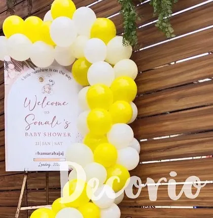 A personalized welcome sign for Sonali's baby shower, framed by a bright yellow and white balloon arch. This is a great way to greet guests as they arrive at the celebration.