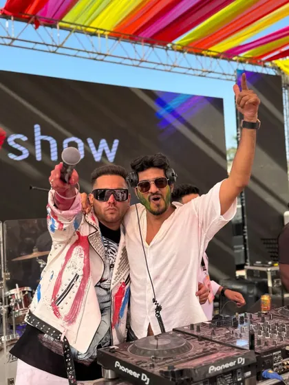 Sharing the stage and the mic during the Holi festival. It's all about collaboration and creating a shared experience of high-energy fun.
