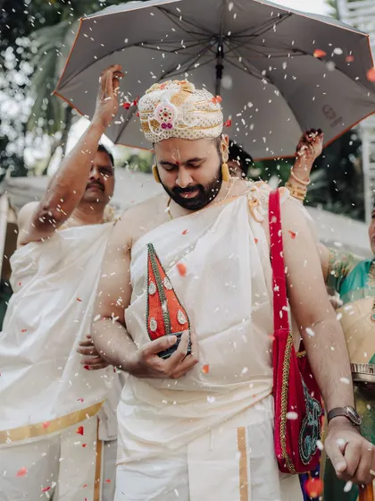The groom's procession, or Kashi Yatra, is a significant part of a South Indian wedding. Here he is showered with rice and flowers, a vibrant and symbolic moment captured candidly.