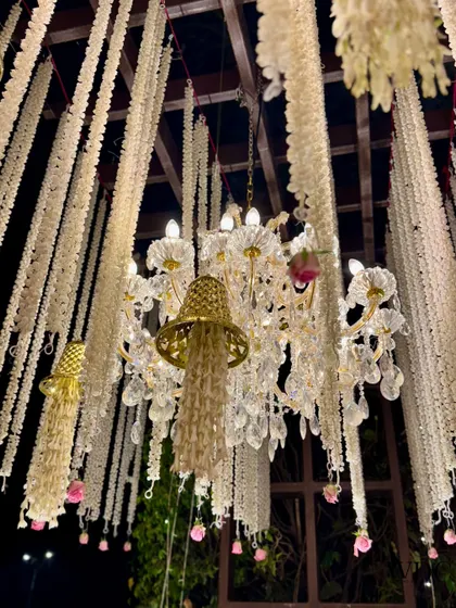 A close-up of the ethereal ceiling, where strings of white flowers hang alongside crystal chandeliers, creating a magical, dream-like effect.