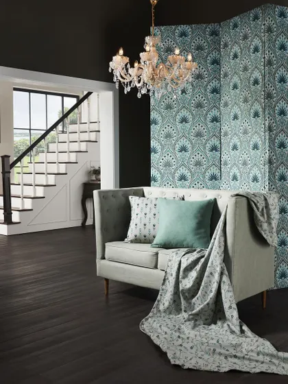 A dramatic interior featuring a patterned room divider and a classic sofa. The crystal chandelier and dark wood floors add a touch of old-world glamour, showcasing luxury fabric in an opulent setting.