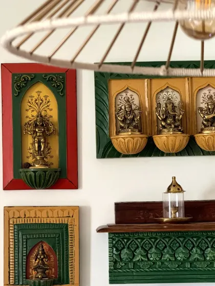 A close-up of the colorful, hand-carved wooden frames holding idols. This detail highlights the traditional craftsmanship I incorporate into my modern designs.