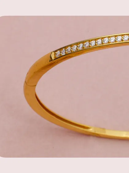 A close-up of a gold kada inspired by the classic nail bracelet design, featuring a line of sparkling diamonds. This piece is the epitome of modern luxury and a must-have for fashion-forward retailers.