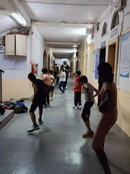 A group of students practices basic fencing stances. Mastering the 'en garde' position and proper posture is crucial for balance and effective movement on the strip.