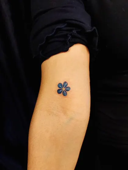 A tiny blue flower, showcasing our ability to work with color in minimalist designs. This piece is a delicate and beautiful statement.