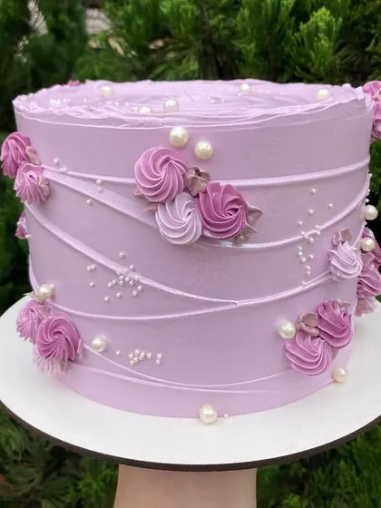 Wrapped in pastel elegance, this dreamy lilac cake is adorned with delicate buttercream roses and pearls. The combed texture and soft colors make it a graceful and picture-perfect choice for any celebration.