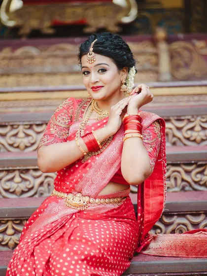 A client looking regal in a red saree with a custom embroidered blouse. The setting and the outfit combine to create a truly royal portrait.
