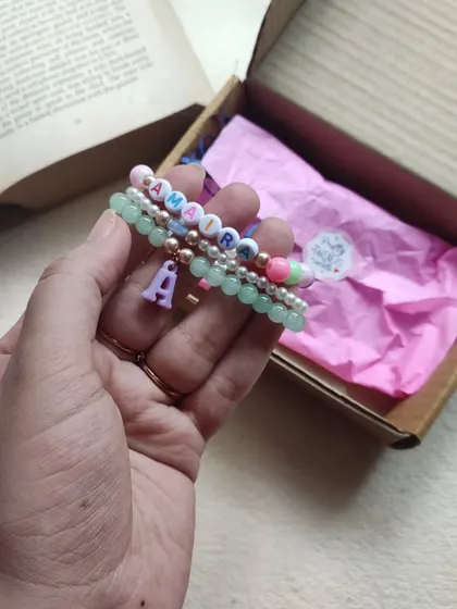 Holding up the three-piece stackable name bracelet for Amara, showing how the different strands complement each other.