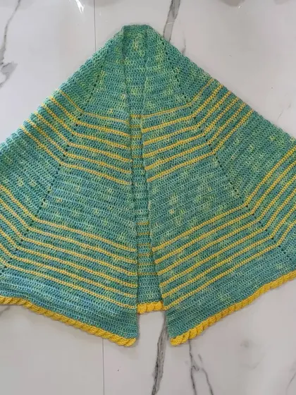 Here is the green and yellow shawl laid flat, showing its classic semi-circle construction. This shape is perfect for a comfortable shoulder wrap.
