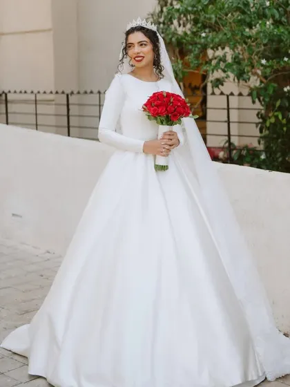 A full-length shot showcasing her magnificent ball gown and long veil. The pop of red from her bouquet is a perfect contrast.