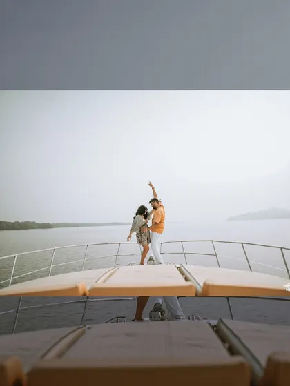A creative shot from the deck of a yacht, capturing the couple dancing against the open water, showcasing a fun and dynamic pre-wedding session.