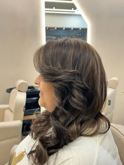 A side profile of a fresh hair color, showing how the face-framing layers and soft curls complement the new shade and bring out the client's features.