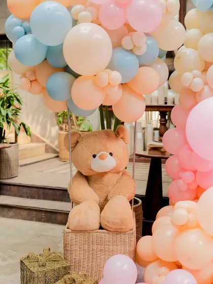 A cuddly teddy bear ready for an adventure in a wicker basket hot air balloon, a key element of our travel and adventure-themed baby showers.