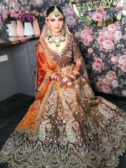 A full view of a bride in a multi-panel lehenga with peacock motifs, a very unique and artistic piece.