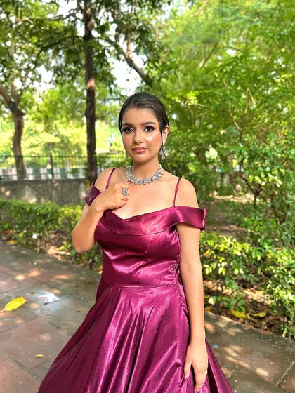 A portrait shot of a model in our wine-colored trail gown, showcasing its off-shoulder neckline and the rich satin fabric.