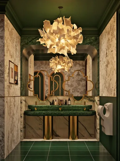 The men's washroom at Koko Hyderabad features rich emerald green marble and tiles, custom wallpaper, and a dramatic floral chandelier, creating a space with its own unique, luxurious personality.