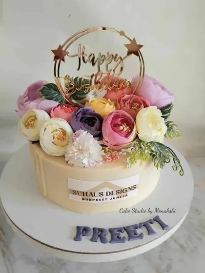 A beautiful floral birthday cake for a corporate brand, made with no fondant. The cake is topped with a crown of colourful flowers and a custom acrylic topper.