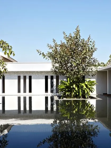 The serene courtyard of the spa at Club Mahindra, Lake Pawana. The design uses water as a reflective surface to amplify the sense of peace, with minimalist white colonnades and strategically placed greenery creating a tranquil, enclosed world for relaxation.