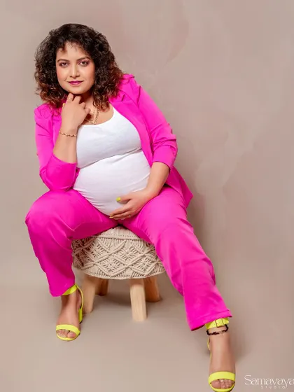 A relaxed and confident seated pose. The combination of the bright pink suit and neon heels shows off the client's fun personality.