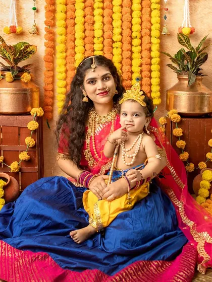 This mother and her little Kanha share a sweet moment against a backdrop of festive marigold flowers.