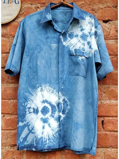 The "after" shot of a plain shirt transformed with indigo tie-dye. The beautiful floral burst patterns are a testament to the creative possibilities of upcycling with natural dyes.